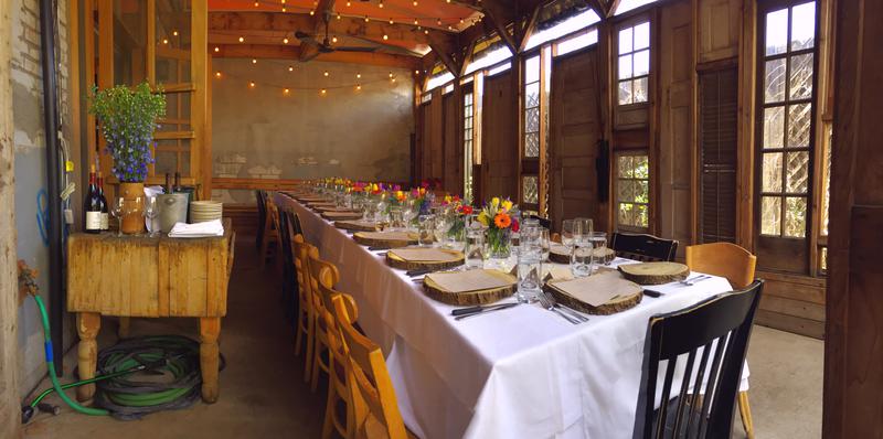 A long private-event table set beneath flowers and warm lights at Potager
