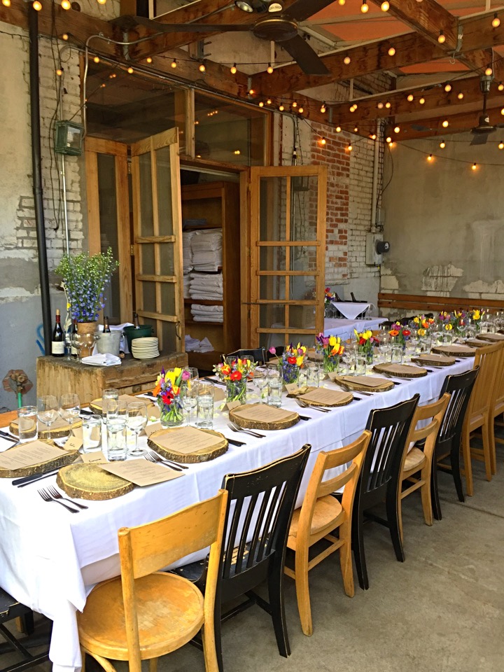 A flower-lined private-event table set with plates and glassware at Potager